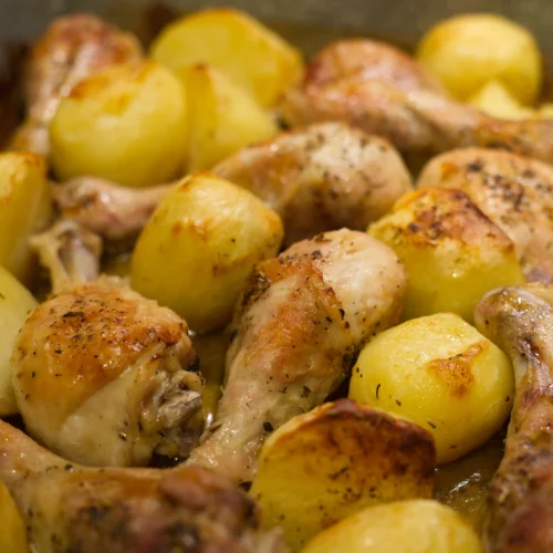 Brown chicken drums and baked potatoes close up