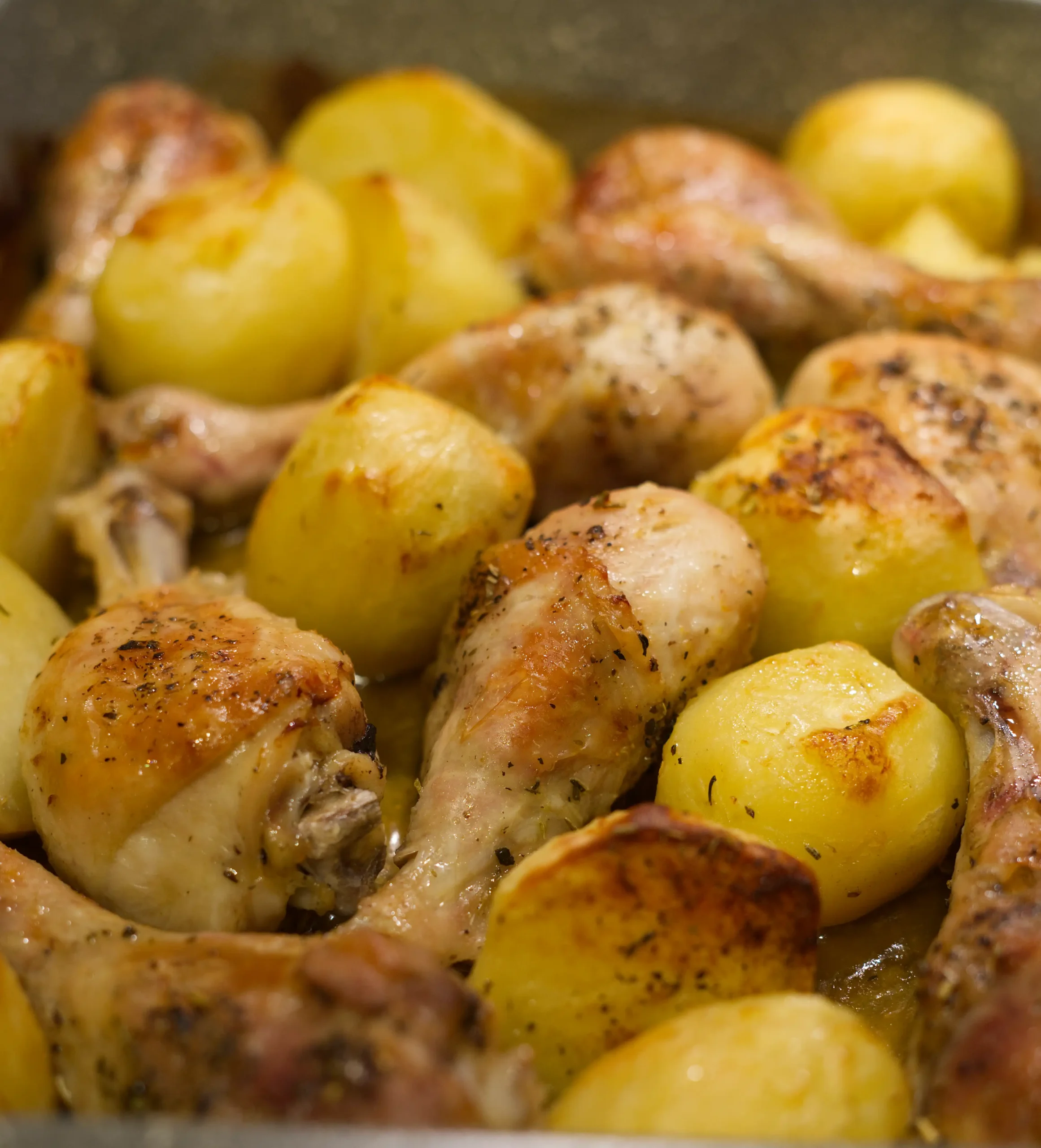 Brown chicken drums and baked potatoes close up